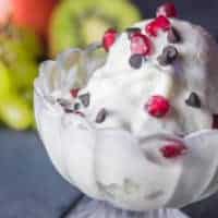 How To Make Corn Rasagulla Ice-cream Corn-rasgulla-icecream on a glass bowl with a piece of corn rasagulla in it covered with vanilla icecream and garnished with some choco chips and pomogranate with a dark background |