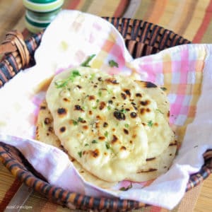 How To Make Garlic Naan Recipe on Tawa and Pressure Cooker Garlic Naan in a basket with greased butter and garlic mixture some coriander leaves