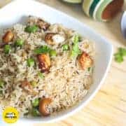 21 Paneer Recipes in Hindi - पनीर व्यंजन हिंदी में Matar paneer pulao in a white bowl with some coriander leaves kept on a wooden surface with top wooden bowlsin the background |