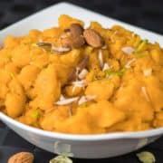 7 Easy And Quick Vrat And Upvas Recipes Moongdal ka halwa on a yellow bowl garnished with some chopped almonds keeped on a red hankerchief with a dark background |