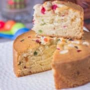 12 Tasty and Easy Cake Recipes Tutti frutti Cake on a white plate with a slice cut of cake on the top of rest of the cake |