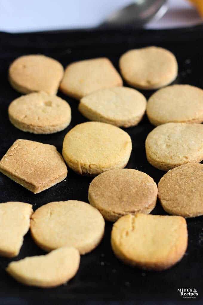 Atta Cookies on a black plate with some coffee in the cup with a spoon