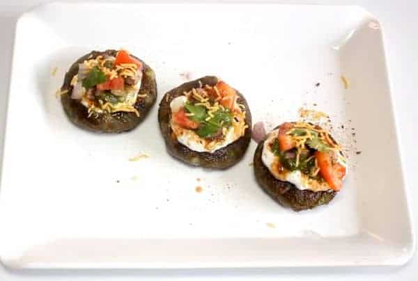 Aloo Palak Tikki Chaat on a white tray garnished with some chaat masala and sev