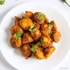 Besan Arbi Ki Sukhi Sabzi on a white plate with some coriander leaves and some green chilli on the background |