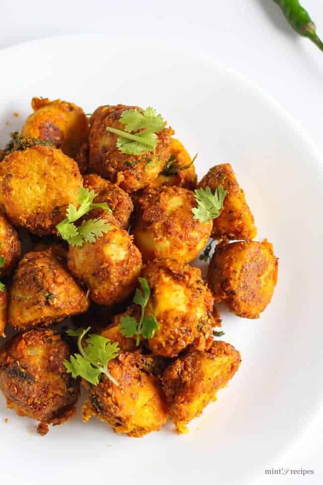 Besan Arbi Ki Sukhi Sabzi on a white plate with some coriander leaves and some green chilli on the background | 