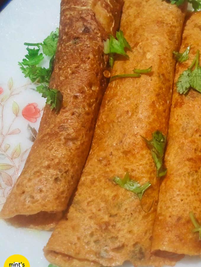 Besan ka chilla on a floural print plate with some garnishing of coriander leaves