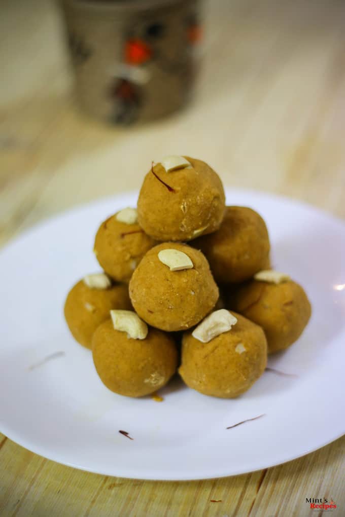 Besan Ke Laddu on a white plate with some cashew and saffron used to garish the laddu kept on a wooden surface 