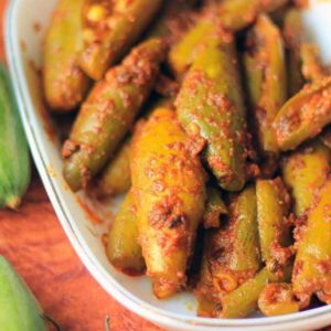 Bharwa Parval on a white bowl putted on a dark coloured surface with some green chili and some parval on the background |