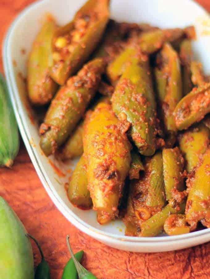 Bharwa Parval on a white bowl putted on a dark coloured surface with some green chili and some parval on the background |