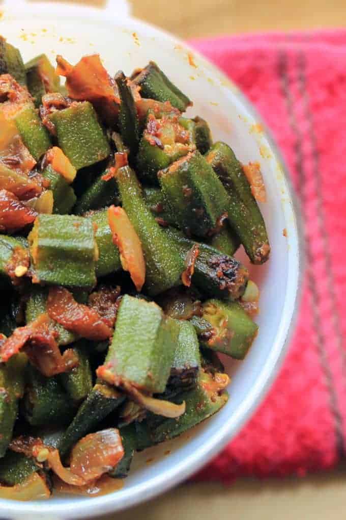Bhindi Do Pyaza on a white bowl putted on a red handkerchief on light surface|