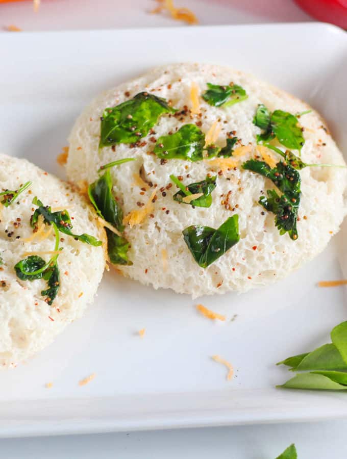 Bread Idli on a white tray with some tempering of mustard seed