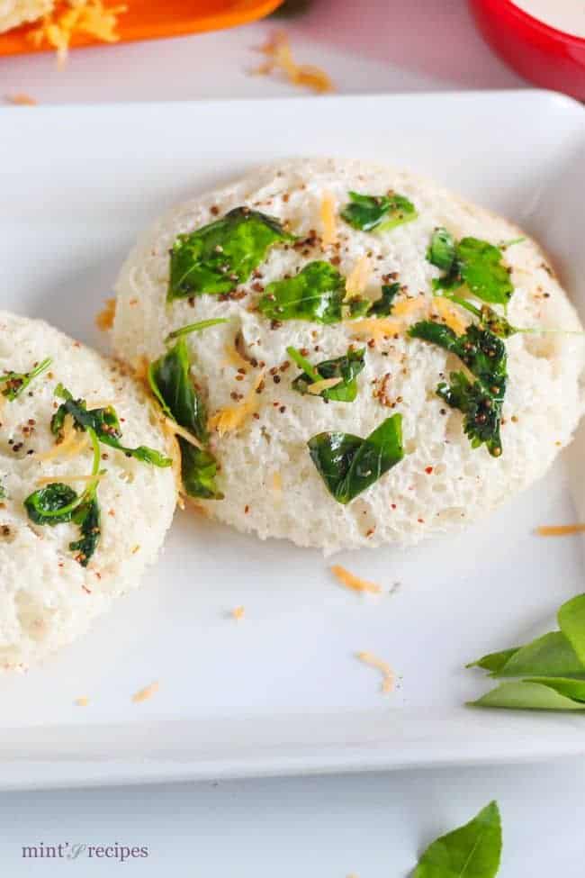 Bread Idli on a white tray with some tempering of mustard seed