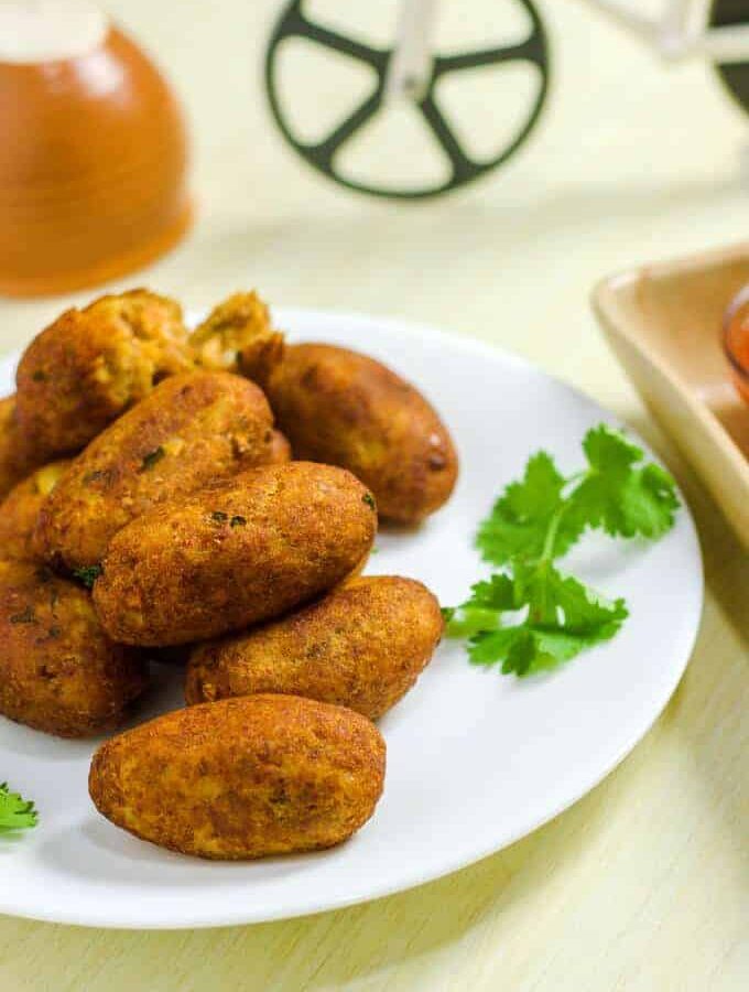 Bread Roll of Left Over Bread on a white plate with some bread rolls and some coriander leaves kept on a wooden surface wit some clay pots on the background |