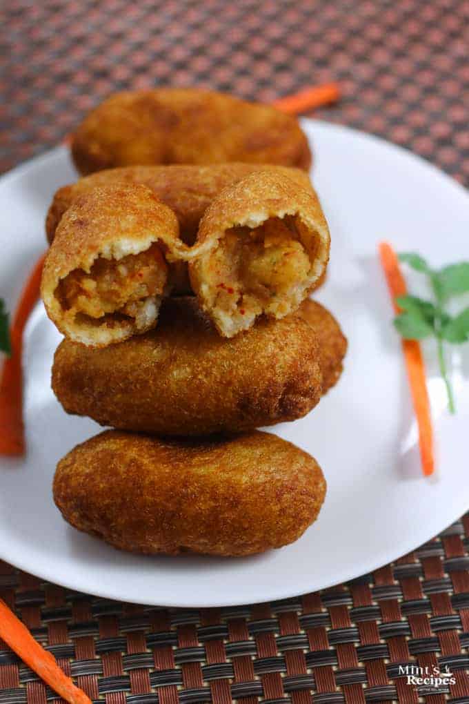 Bread Roll of Left Over Bread on a white plate with some bread rolls and some coriander leaves kept on a wooden surface wit some clay pots on the background |