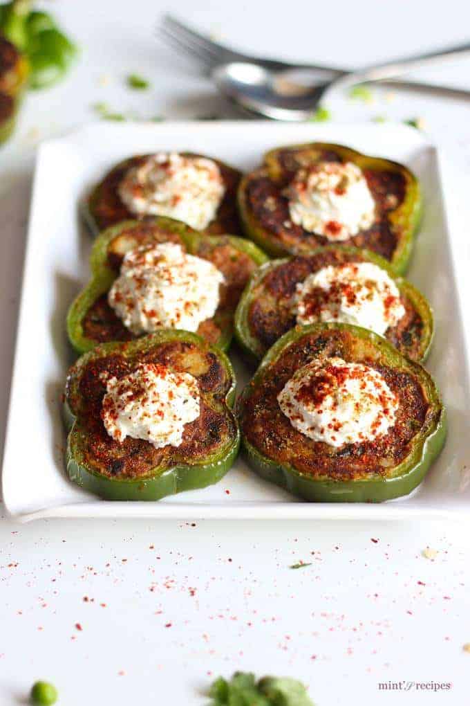 Capsicum Masala Tikki on a white tray with some coriander leaves and green peas