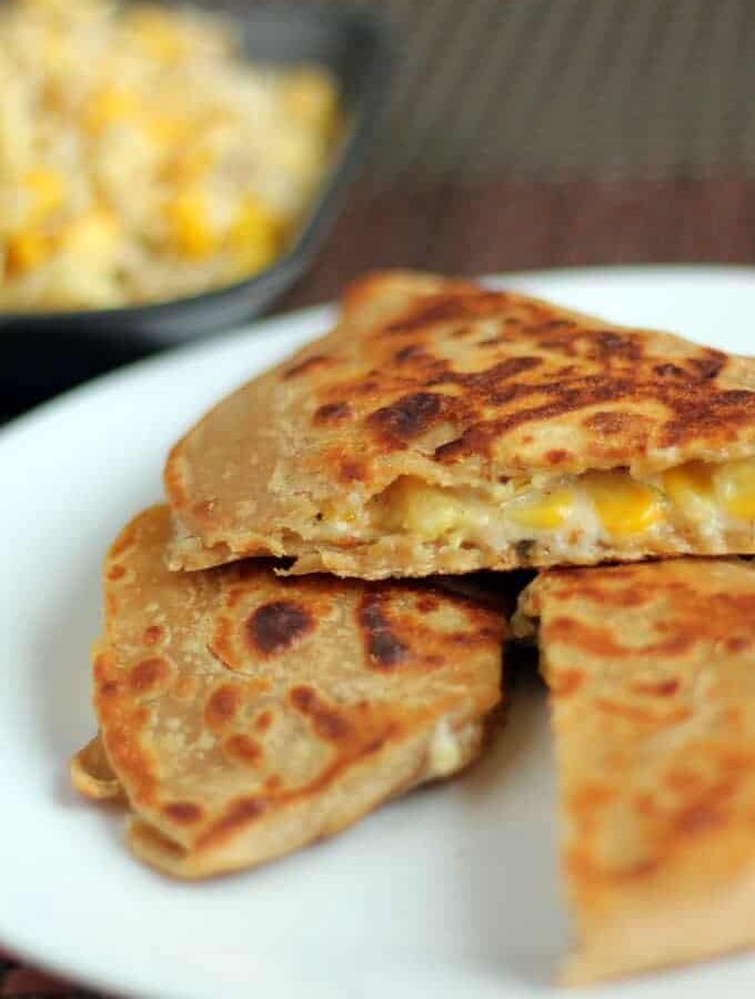 Cheese Corn Pizza Paratha on a white plate with dark background with some cheese corn mixture | www.mintsrecipes.com |