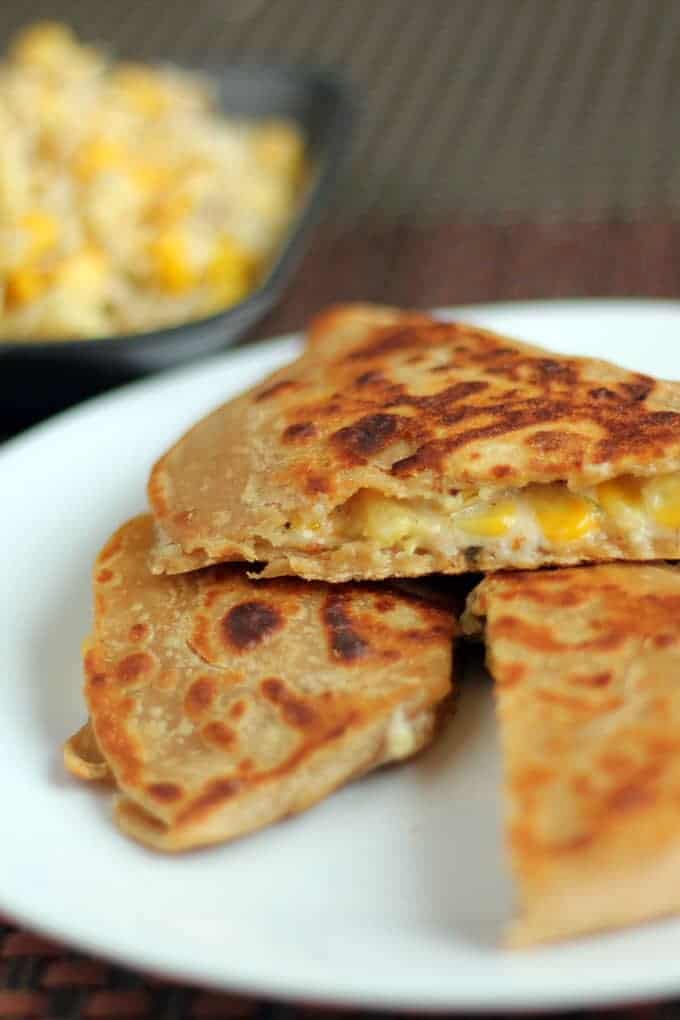 Cheese Corn Pizza Paratha on a white plate with dark background with some cheese corn mixture