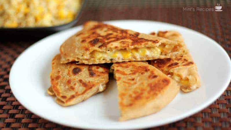 Cheese Corn Pizza Paratha on a white plate with dark background with some cheese corn mixture | www.mintsrecipes.com |