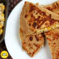 Cheese Corn Pizza Paratha on a white plate with dark background with some cheese corn mixture |