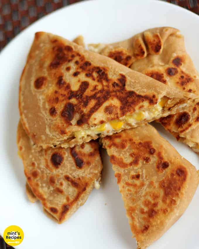Cheese Corn Pizza Paratha on a white plate with dark background with some cheese corn mixture