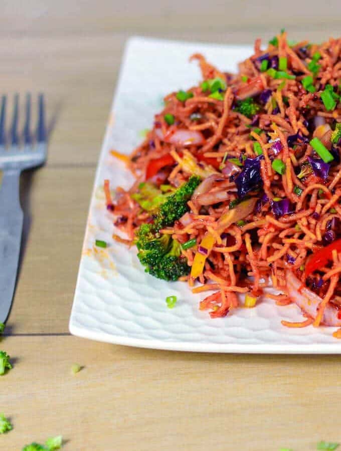 Chinese salad on a white plate garnishing with some spring onion and broccoli kept on wooden surface