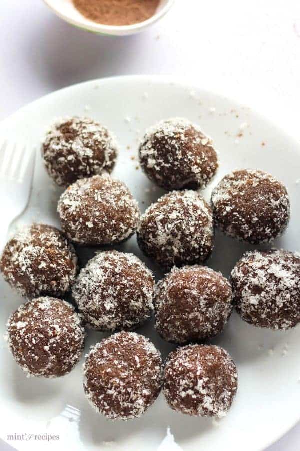 Chocolate coconut balls on a white plate garnished with some dessicated coconut 
