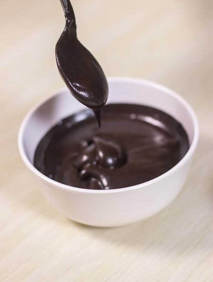 Chocolate Frosting Using Cocoa Powder on a white bowl kept on a wooden surface