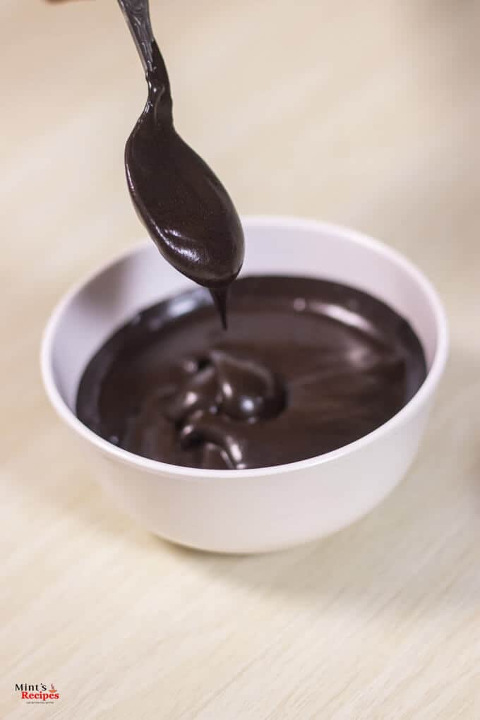 Chocolate Frosting Using Cocoa Powder on a white bowl kept on a wooden surface 