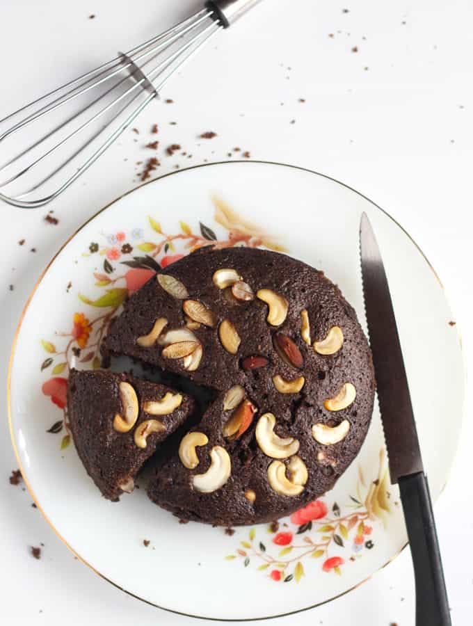 Chocolate Eggless Rava Cake In a floural print plate with slice of suji cake and a knife on the side of the cake