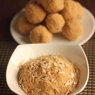 Rajasthani Churma Laddoo on a white plate putted on a mat and a bowl full of churma with some almonds garnished on it |