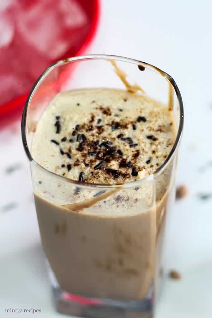 Cold Coffee on a glass with some ice cubes and chocolate syrup and sprinklers