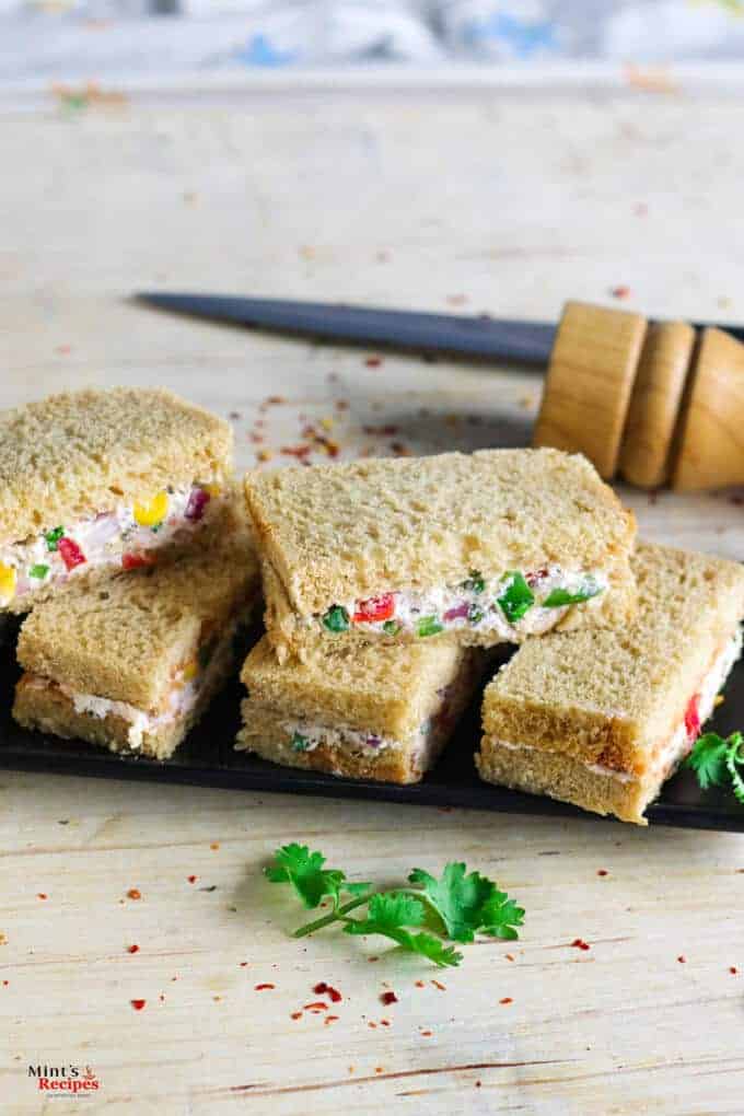 Cream Cheese Sandwich on a black plate for garnishing some coriander leaves and some chilli flakes|