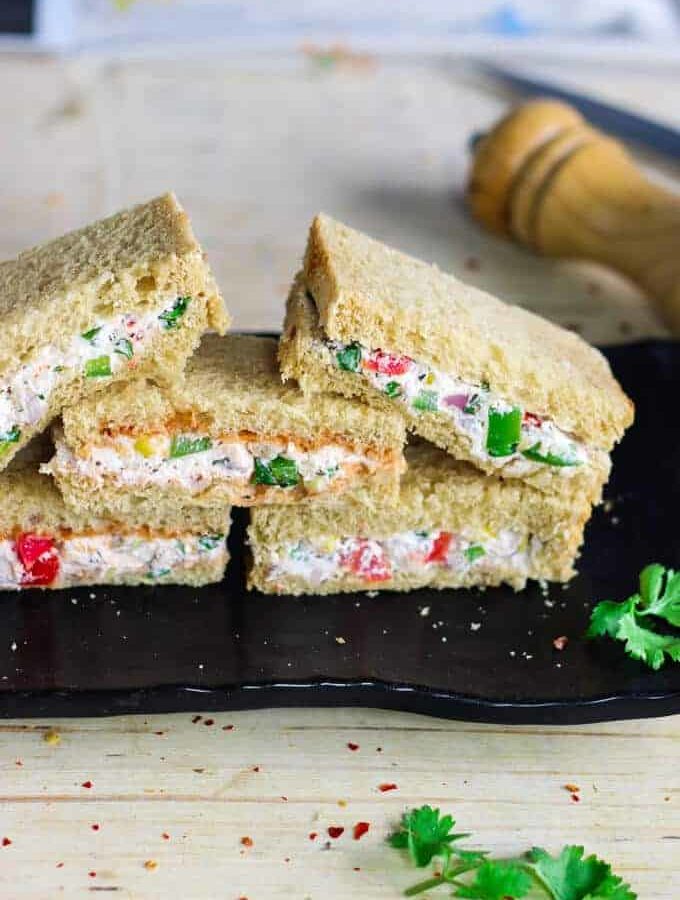 Cream Cheese Sandwich on a black plate for garnishing some coriander leaves and some chilli flakes|