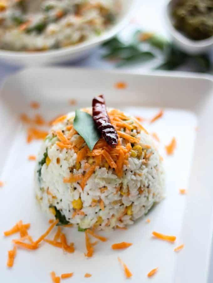 Curd Rice on a white tray with some grated carrot