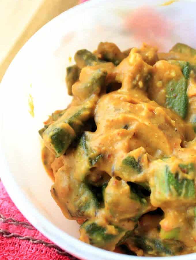Dahi Bhindi on a white bowl put on a red surface. it's quick and very easy recipes to make at home |