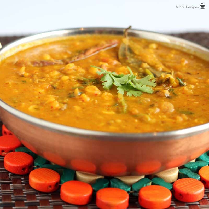 Dal fry on a heavy vessel kept on a wooden stand with a big spoon besides it