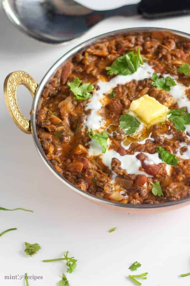 Dal Makhani on a deep heavy pan on a white surface. garnished with butter and cream with some coriander leaves