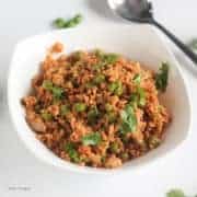 Dry Soya Peas on a white bowl with garnished some coriander leaves on a white background with a spoon |