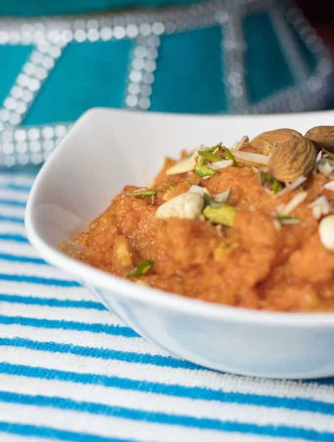 Gajar ka Halwa on a glass bowl garnished with chopped almonds and cashews |