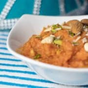 Gajar ka Halwa on a glass bowl garnished with chopped almonds and cashews | www.mintsrecipes.com |