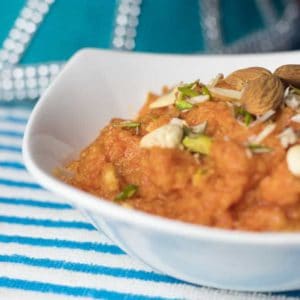 Gajar ka Halwa on a glass bowl garnished with chopped almonds and cashews | www.mintsrecipes.com |