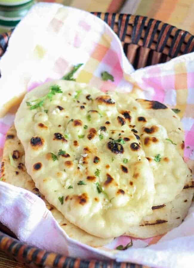 Garlic Naan in a basket with greased butter and garlic mixture some coriander leaves