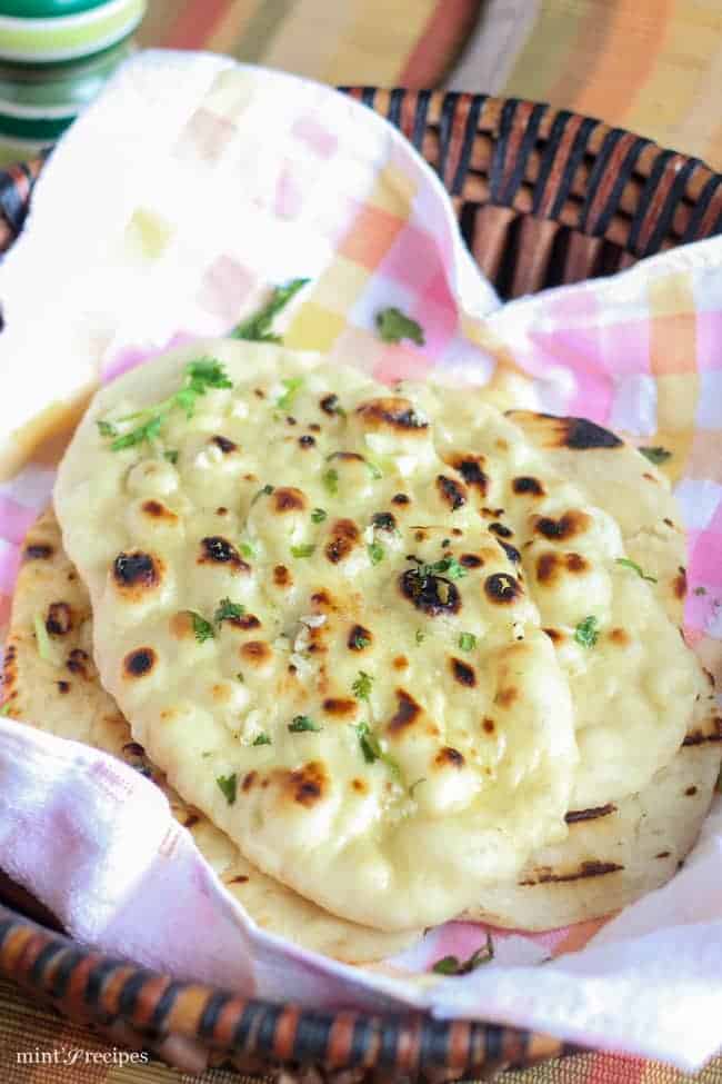 Garlic Naan in a basket with greased butter and garlic mixture some coriander leaves 