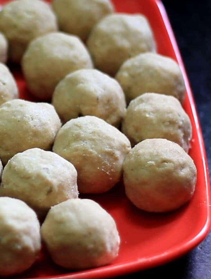 Gond-ke-laddu on a red plate with lots of pieces of laddu's on it with dark background |