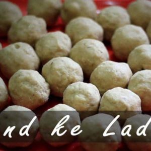 Gond-ke-laddu on a red plate with lots of pieces of laddu's on it with dark background |