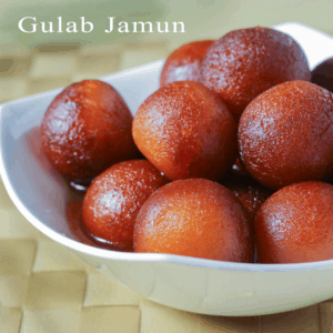 Gulab Jamun on a white bowl with lots of gulab jamun kept on a mattress