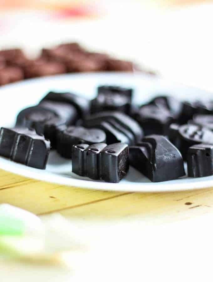 Chocolates on a white plate with a chocolate mould and wire whisker in the background