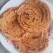 Lacch Paratha recipe | Tasty and soft 3 pcs of laccha paratha on a white flower printed plate kept on a white marble surface |