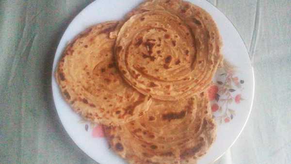 Lacch Paratha recipe | Tasty and soft 3 pcs of laccha paratha on a white flower printed plate kept on a white marble surface |