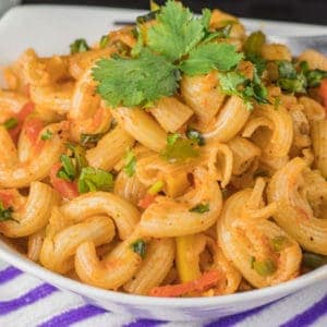 Indian style macaroni on a white bowl garnished with coriander leaves